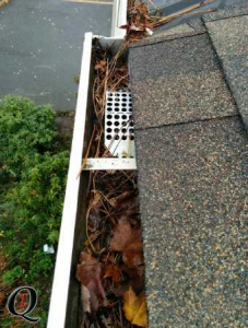 aluminum gutters full of debris with gutter basket installed at downpipe